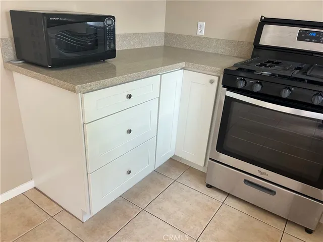 a kitchen with granite countertop white cabinets and stainless steel appliances
