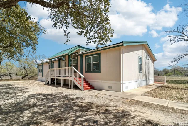 a kitchen with stainless steel appliances granite countertop a refrigerator a sink dishwasher a stove with white cabinets and wooden floor