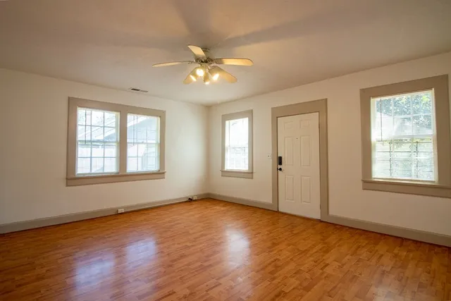 a view of an empty room with a window and wooden floor