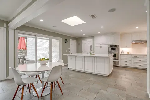 a kitchen with stainless steel appliances kitchen island granite countertop a table chairs sink and cabinets