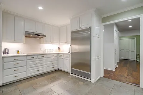 a kitchen with granite countertop a refrigerator and white cabinets