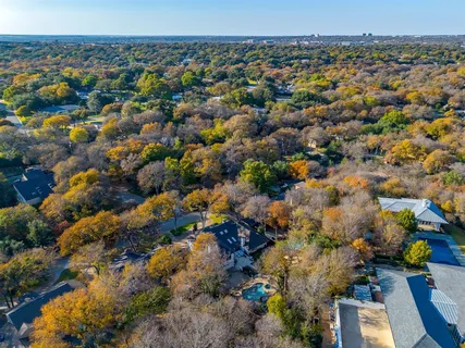 an aerial view of a residential houses with outdoor space and trees
