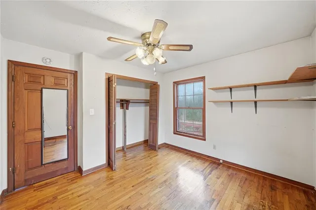 an empty room with wooden floor fan and windows