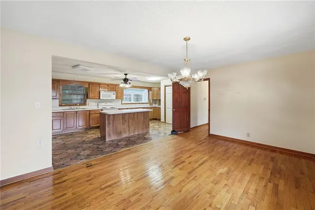 an empty room with wooden floor and kitchen view