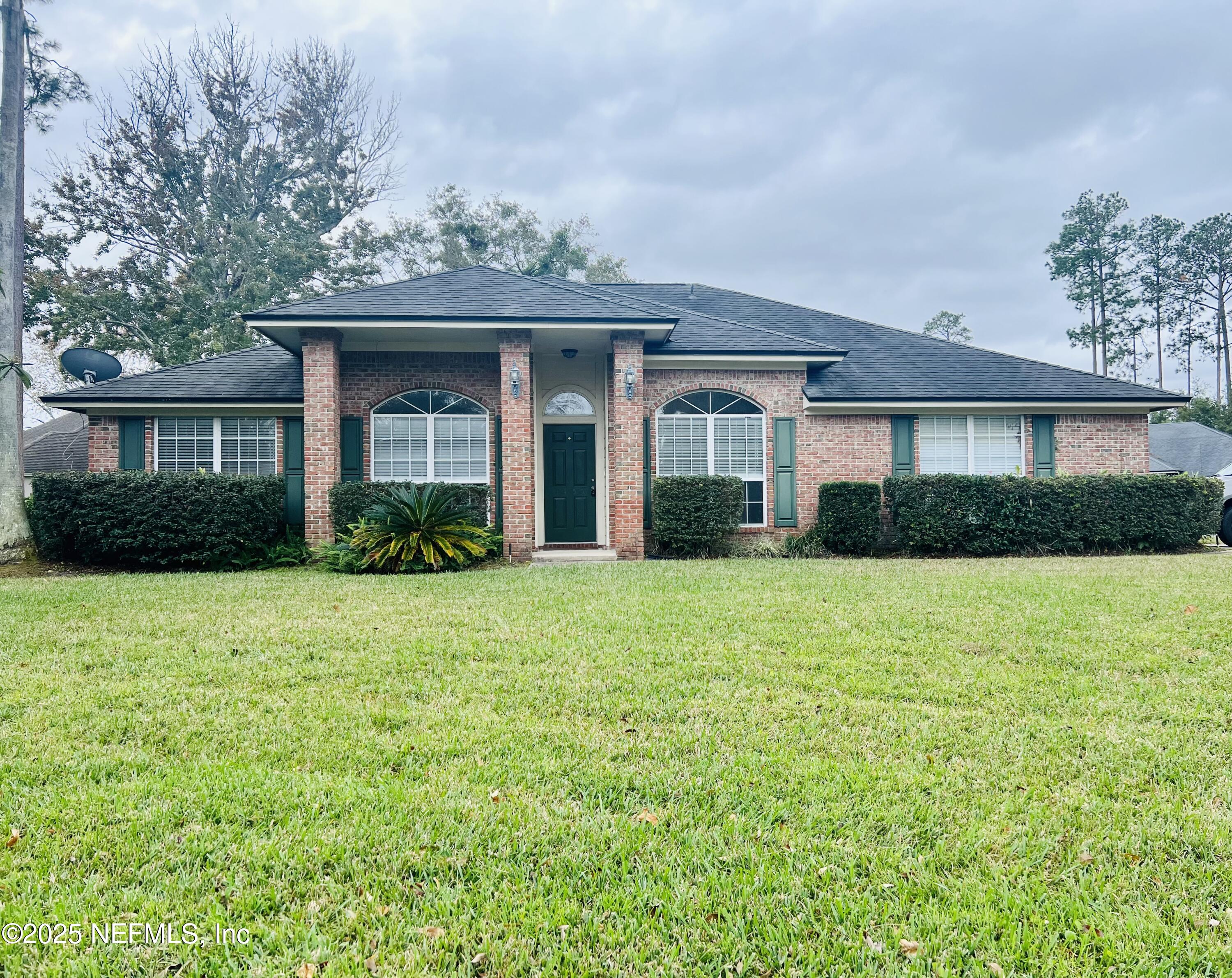 1455 Silver Bell Lane Fleming Island, FL 32003 - Photo 1 of 37 a view of a brick house with a yard and potted plants