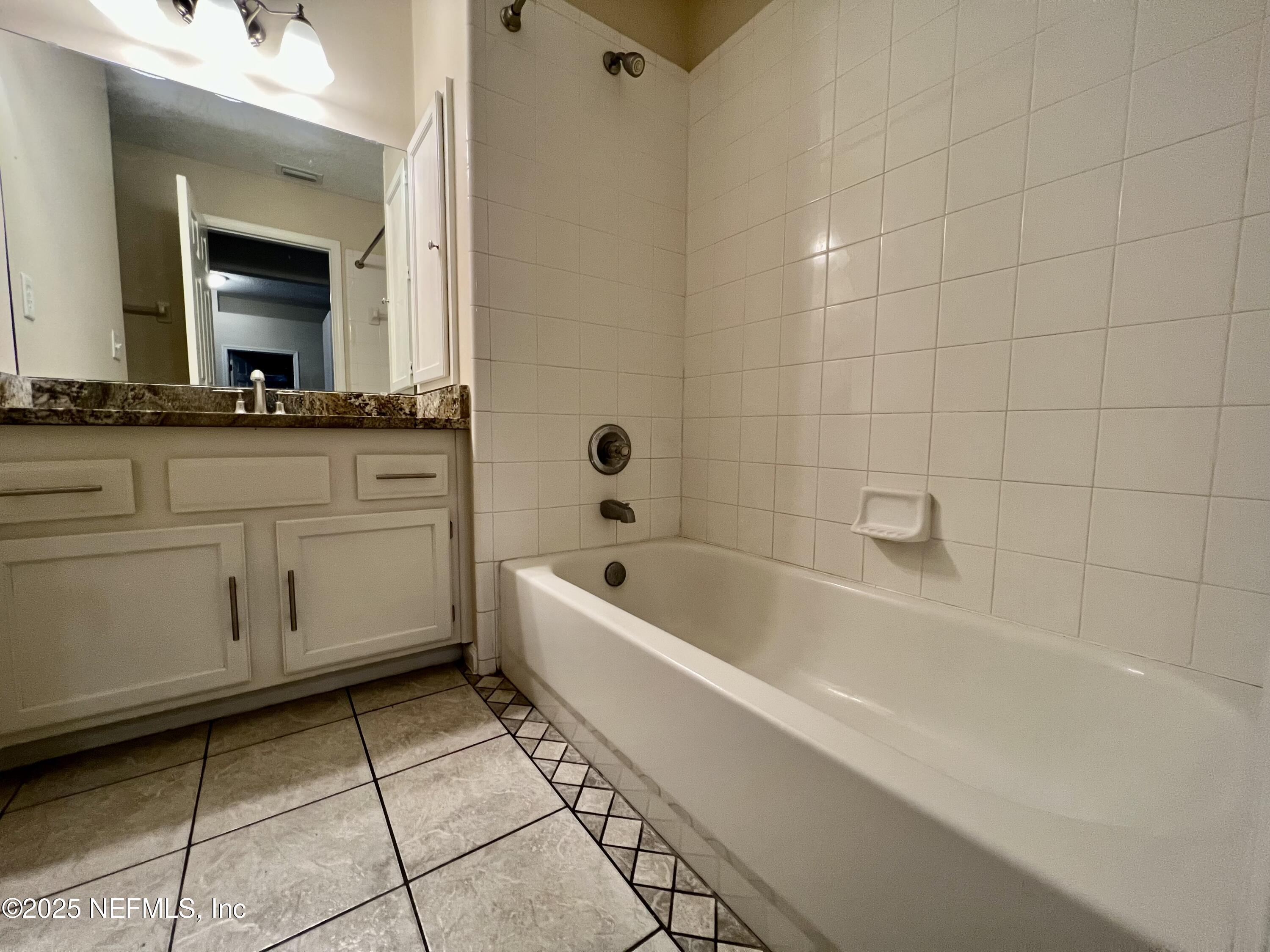 1455 Silver Bell Lane Fleming Island, FL 32003 - Photo 14 of 37 a bathroom with a bathtub a mirror a sink and a shower