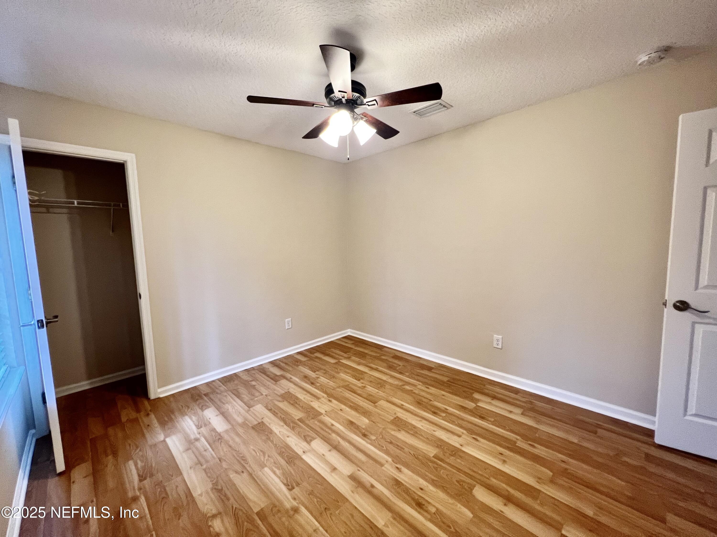 1455 Silver Bell Lane Fleming Island, FL 32003 - Photo 19 of 37 an empty room with wooden floor fan and windows