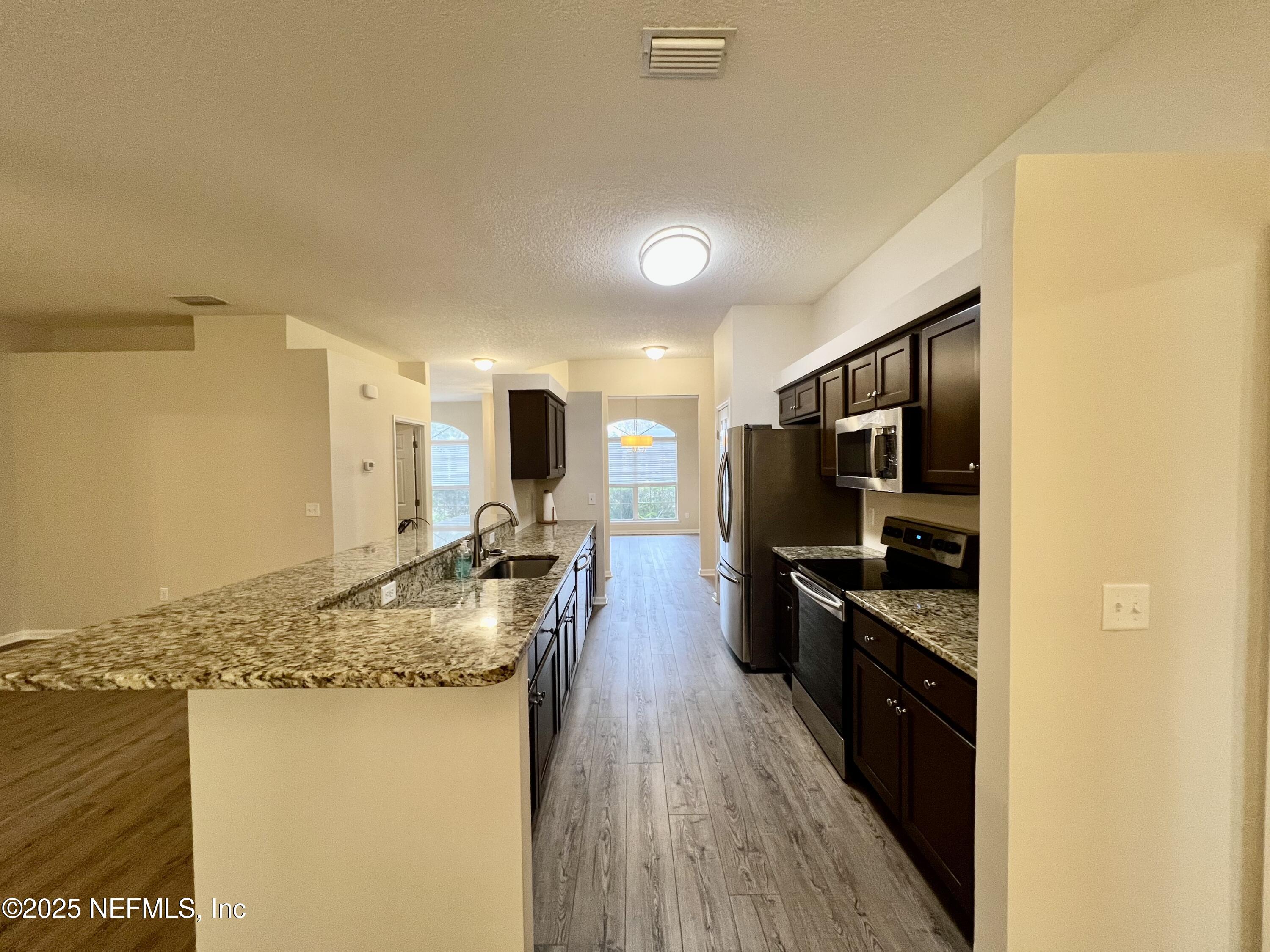 1455 Silver Bell Lane Fleming Island, FL 32003 - Photo 9 of 37 a kitchen with stainless steel appliances granite countertop a sink stove and refrigerator