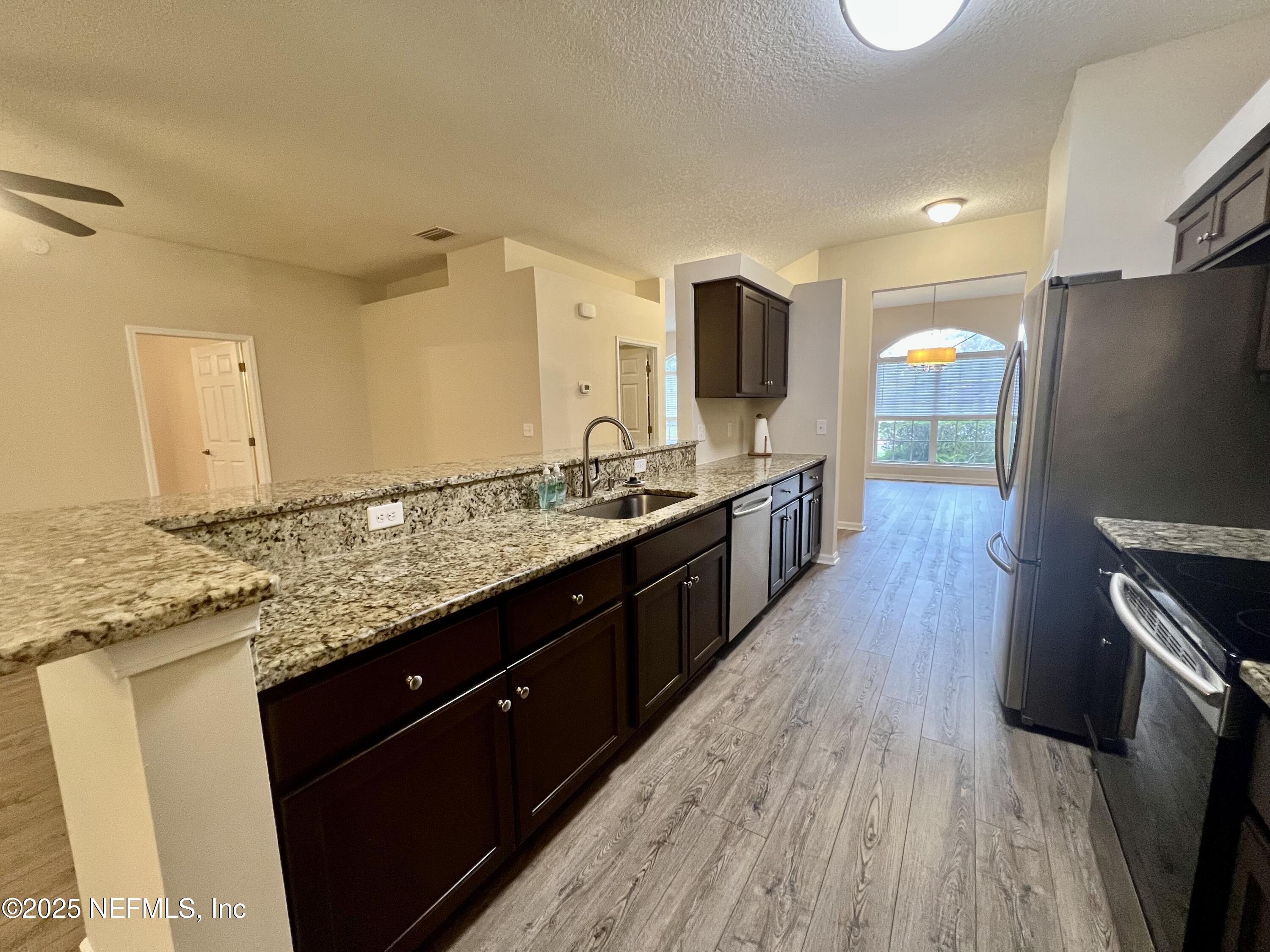 1455 Silver Bell Lane Fleming Island, FL 32003 - Photo 10 of 37 a large kitchen with stainless steel appliances granite countertop a sink stove and refrigerator