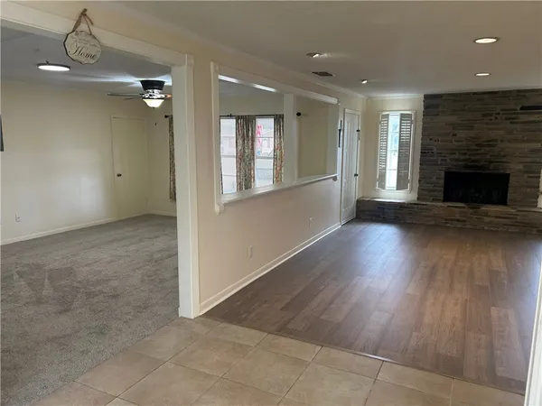 an empty room with wooden floor fireplace and windows