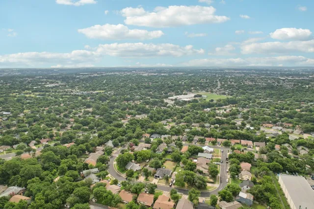an aerial view of residential houses with outdoor space and trees
