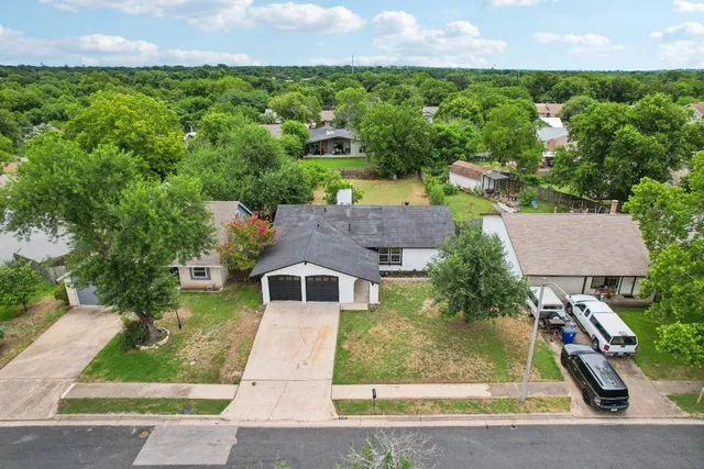 an aerial view of residential houses with outdoor space and trees