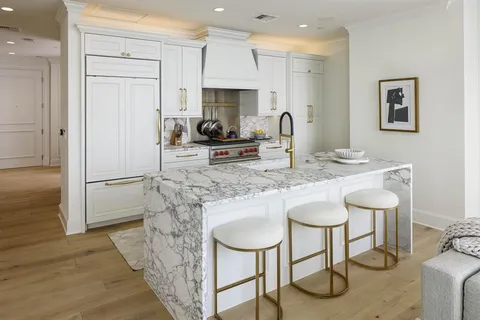 a kitchen with stainless steel appliances granite countertop a dining table chairs refrigerator and sink