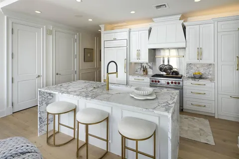 a kitchen with stainless steel appliances granite countertop a stove a sink a dining table and chairs