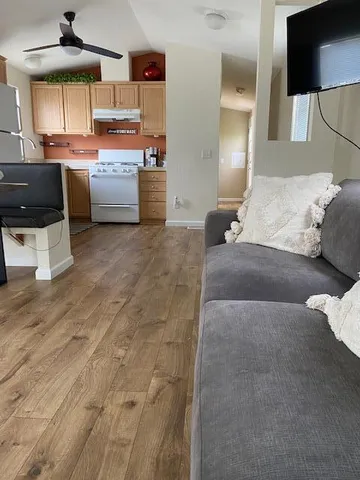 a living room with couches and kitchen view with wooden floor
