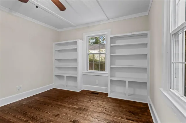 a view of an empty room with a window and wooden floor