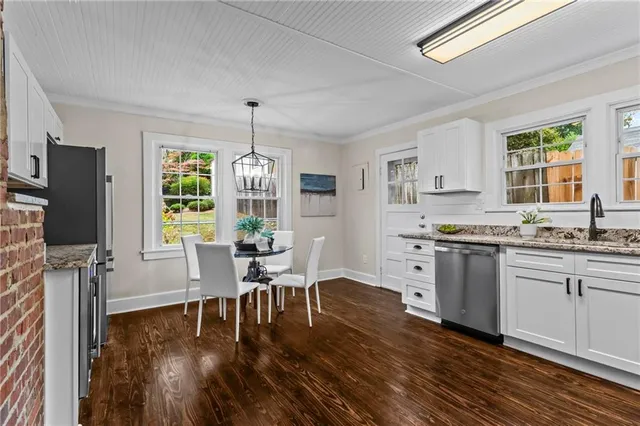 a kitchen with stainless steel appliances granite countertop a stove top oven a sink dishwasher a dining table and chairs with wooden floor