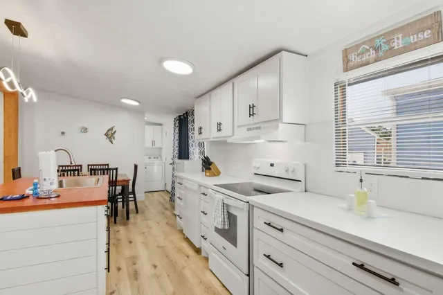 a kitchen with kitchen island a sink white cabinets and appliances