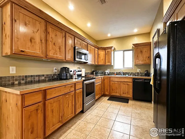a large kitchen with stainless steel appliances granite countertop a stove a sink dishwasher and a refrigerator