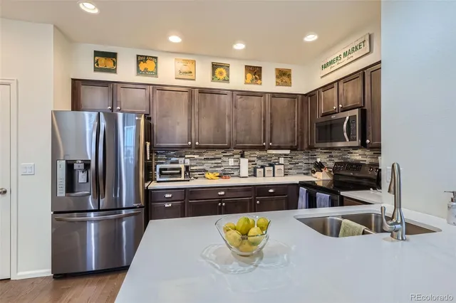 a kitchen with stainless steel appliances granite countertop a refrigerator and a stove top oven