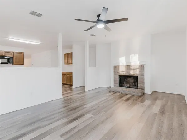 a view of an empty room with wooden floor fireplace and a window