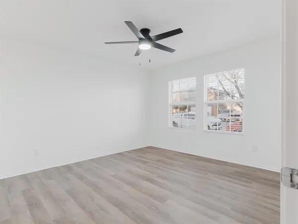 an empty room with wooden floor and windows