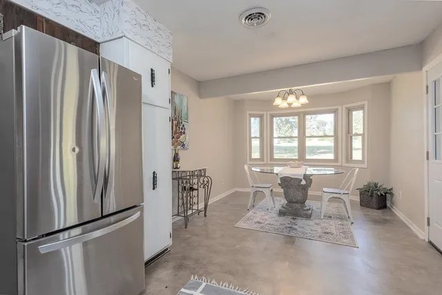 a dining room with furniture a large window and stainless steel appliances