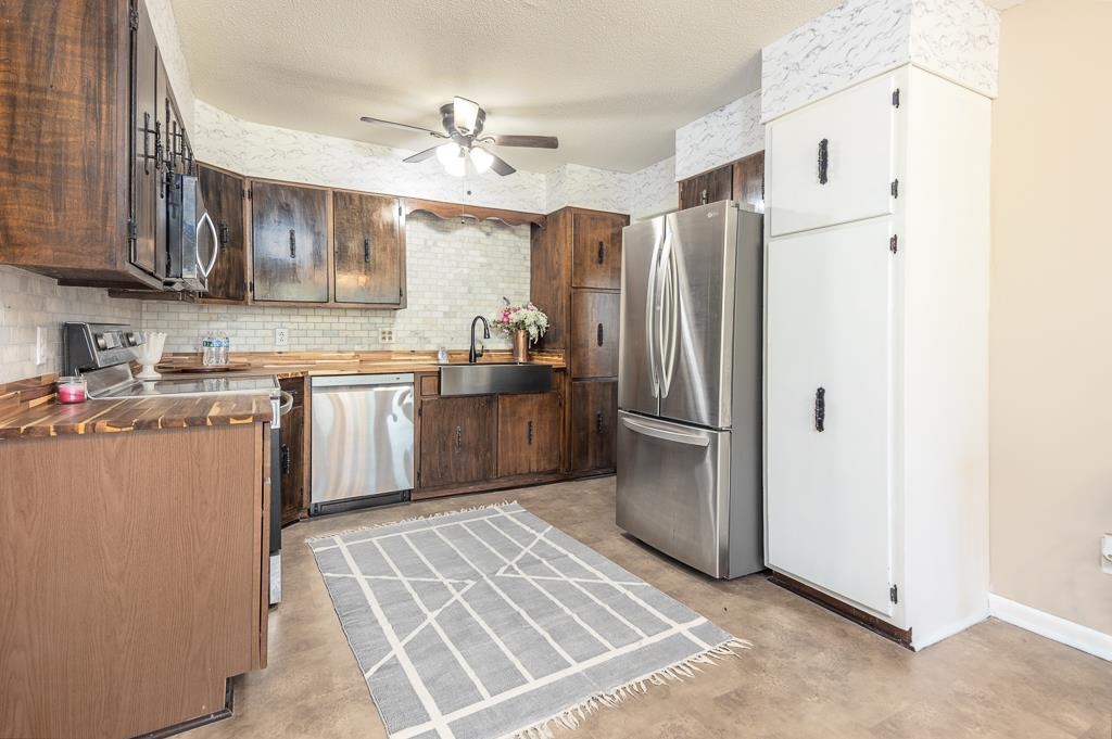 5750 Brighton-Clopton Road Brighton, TN 38011 - Photo 10 of 26 a kitchen with stainless steel appliances granite countertop a refrigerator a sink dishwasher a stove with wooden cabinets