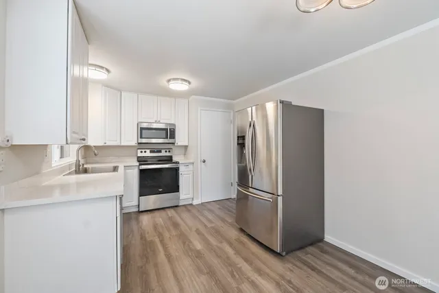 a kitchen with granite countertop a refrigerator stove and sink