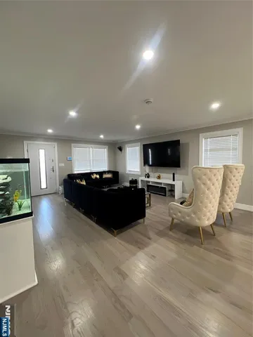 a living room with couches and kitchen view with wooden floor