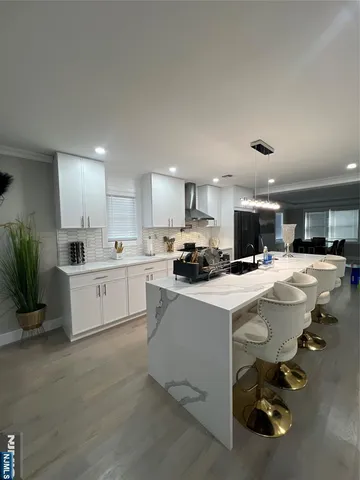 a kitchen with a sink dishwasher a stove a refrigerator and white cabinets with wooden floor