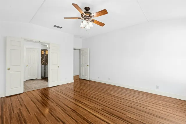 an empty room with wooden floor and a ceiling fan