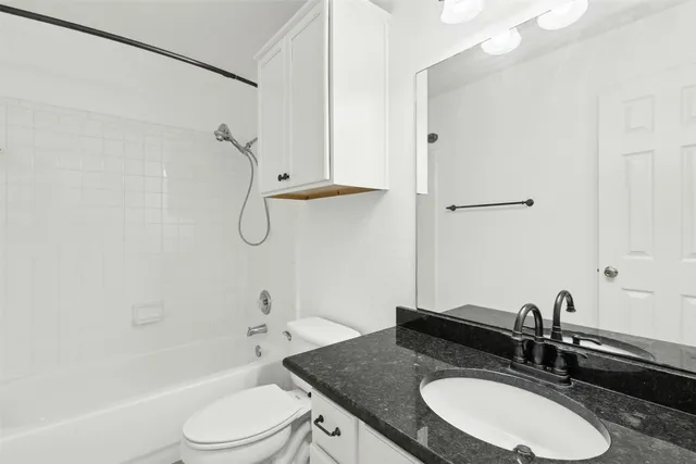 a bathroom with a granite countertop sink toilet a mirror and shower