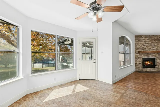 an empty room with windows chandelier and fireplace