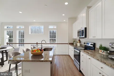 a kitchen with stainless steel appliances granite countertop a sink a stove top oven a counter space and cabinets
