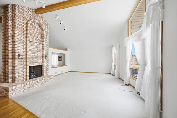 a view of empty room with fireplace and wooden floor