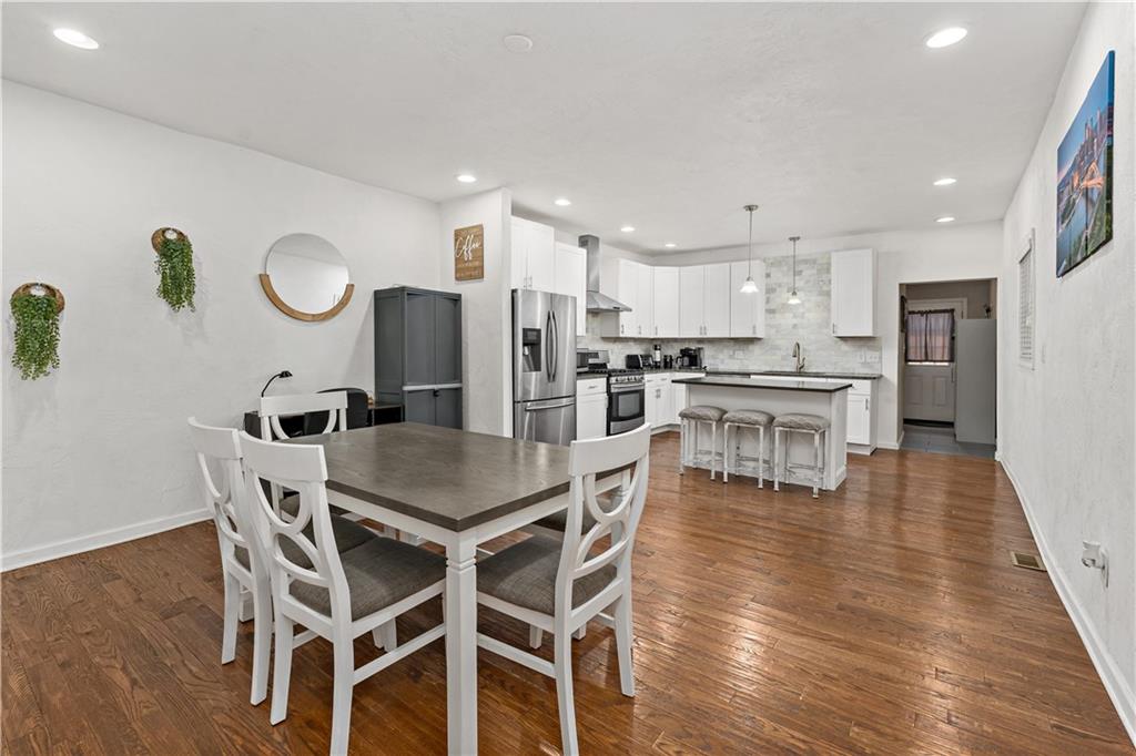 239 Albert Street Pittsburgh, PA 15211 - Photo 5 of 34 a kitchen with stainless steel appliances kitchen island granite countertop a dining table chairs and white cabinets