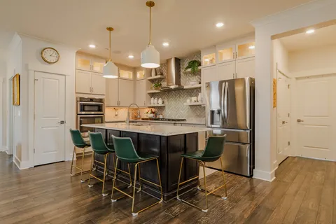 a kitchen with stainless steel appliances granite countertop a refrigerator a stove a sink dishwasher and a dining table with wooden floor
