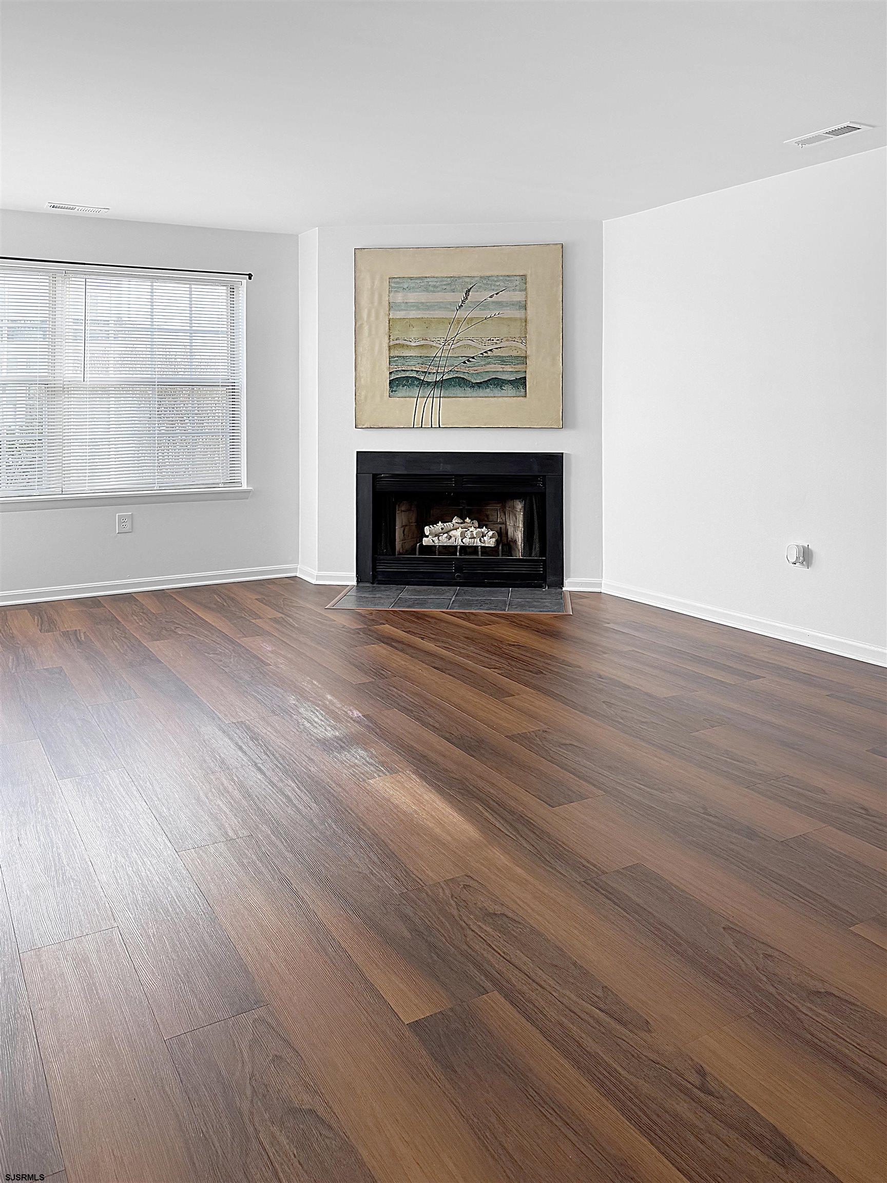 26 Malibu Way, Unit 26 Smithville, NJ 08205 - Photo 2 of 7 an empty room with wooden floor a fireplace and windows