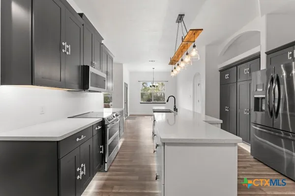 a kitchen with stainless steel appliances a sink stove refrigerator and cabinets
