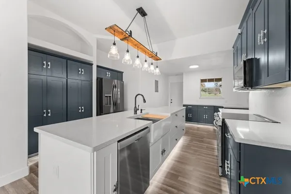 a large kitchen with stainless steel appliances kitchen island granite countertop a sink and a refrigerator