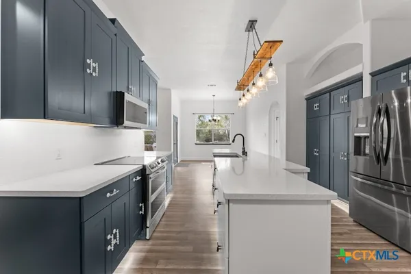 a kitchen with stainless steel appliances granite countertop a sink a stove and a refrigerator