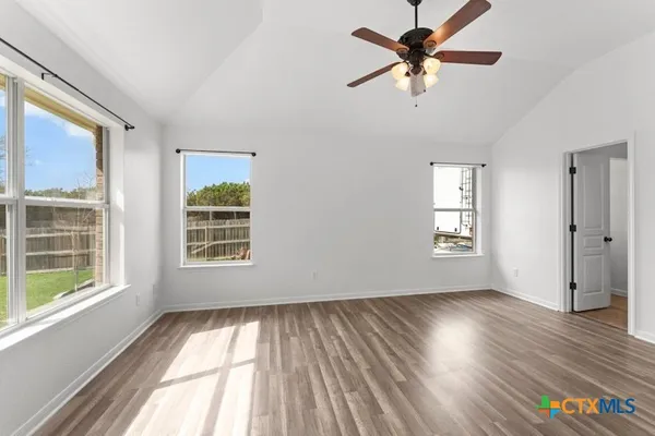 a view of an empty room with a window and wooden floor