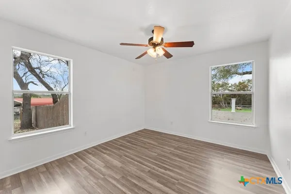 a view of empty room with wooden floor and fan