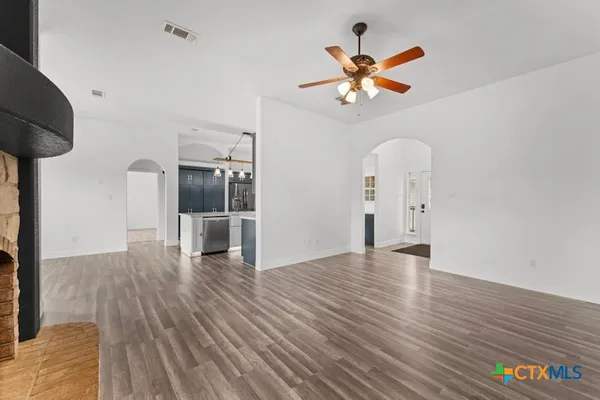a view of empty room with wooden floor and ceiling fan
