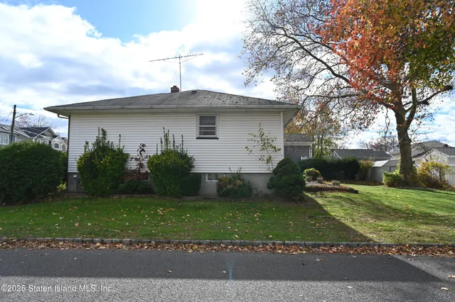 a view of a yard in front of a house with large windows