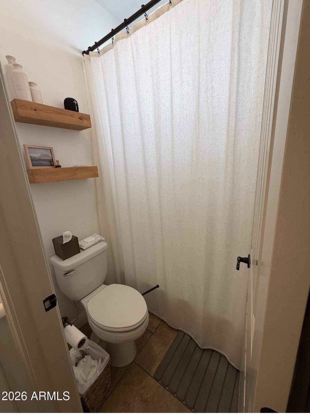 1377 South Chaparral Boulevard Gilbert, AZ 85296 - Photo 13 of 22 a bathroom with a toilet and a shower curtain
