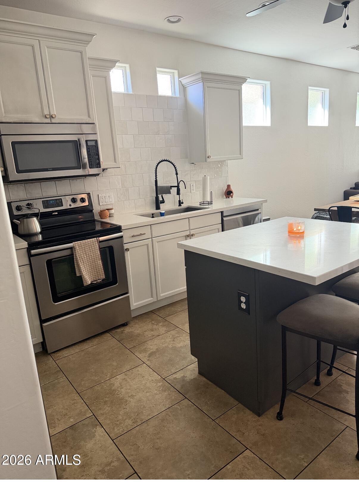 1377 South Chaparral Boulevard Gilbert, AZ 85296 - Photo 9 of 22 a kitchen with stainless steel appliances a sink a stove a microwave a sink a refrigerator and cabinets