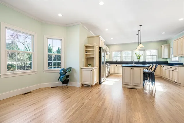 a kitchen with stainless steel appliances granite countertop wooden floor a refrigerator a sink a dining table and chairs