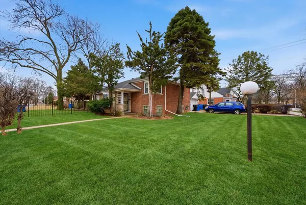 a front view of a house with garden and tree